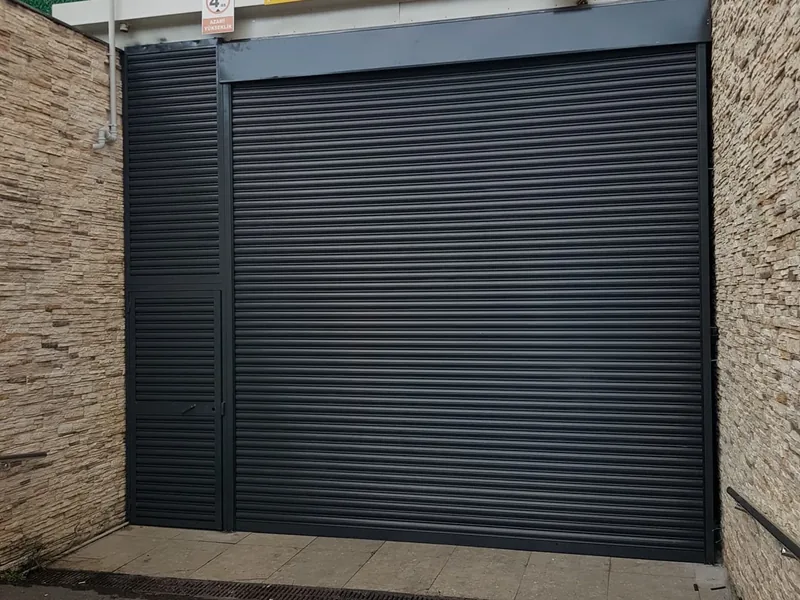 Otopark girişinde antrasit kepenk ve solunda personel kapısı